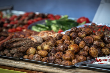 Ukrainian country fair cooking roasted potatoes cooked outdoors cookout vegetable meals fresh organic, healthy snack cooked on grill flame. Street fast food.