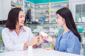 Beautiful asian pharmacist giving drug information to patient in drug store