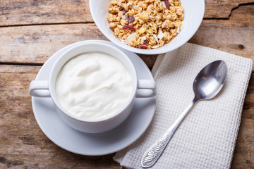 Healthy breakfast background. Muesli with yoghurt in bowl on wooden background