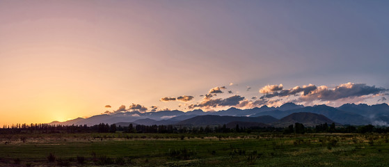 Panorama of a mountain valley in the summer. Amazing nature, mountains lit by sunset, summer, autumn in the mountains. Travel, tourism, beautiful background, picture of nature