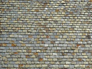 Brown gray old tiles roofs with color variations on a utility roof. Some textures and shades of the material viewable on this old slate roof. Slate material