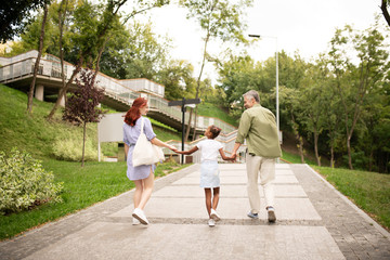Parents walking with adopted girl hand in hand