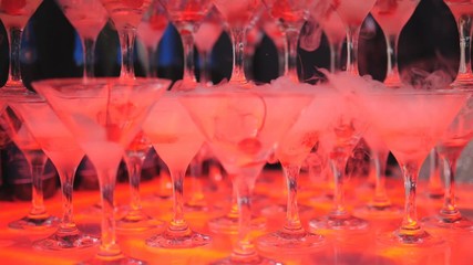 Slide champagne with cherries in the glasses and the smoke from the dry ice on the buffet table, slow motion.