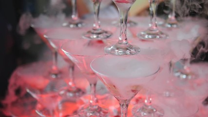The pyramid of glasses with champagne and dry ice at the festival in slow motion.