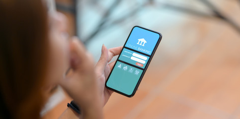 Cropped shot of female doing online banking on smartphone in comfortable workplace