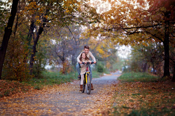 Brother with sister riding bicycle in autumn park