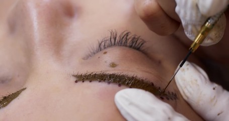 Woman on the cosmetic procedure for the treatment of eyebrows, Microblading in the beauty salon