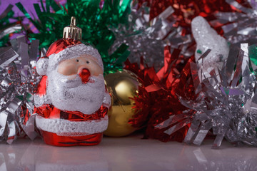 Christmas composition with toy Santa Claus on the background of multi-colored tinsel