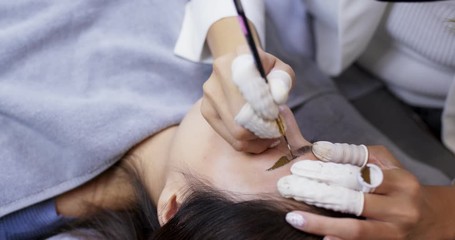 Beautician hands doing eyebrow microblading with ink needle