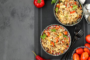 Bulgur with mushrooms and vegetables in a two bowls on a dark background, vegetarian oriental dish, horizontal orientation, copy space, top view