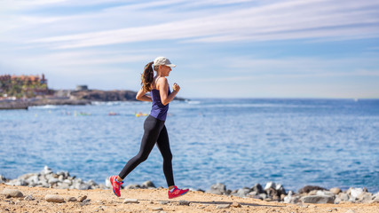 Side view of young woman running near the ocean