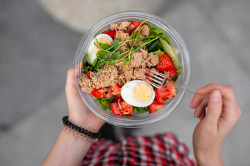 POV woman eating salad at urban city outdoor, dinner snack