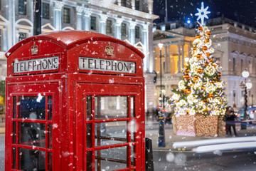 Rote Telefonzelle in London vor einem beleuchtetem Weihnachtsbaum zur Adventszeit, Großbritannien