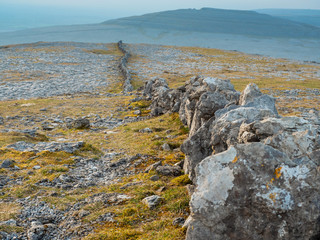 Very long stone fence in a mountains, Burren National park, Ireland, Mountains in the background.