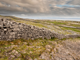 Traditional dry stone wall, inishmore, Aran islands, Ireland, Connemara and Atlantic ocean in the background.
