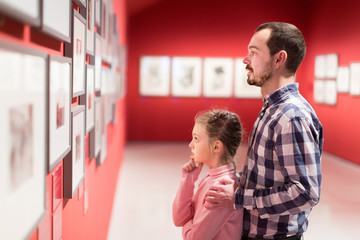 Man and girl exploring exhibition of photos