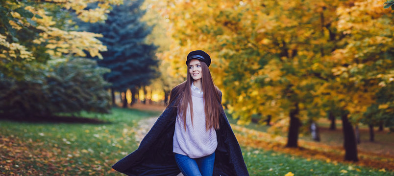 portrait of a happy woman in a coat walking in the autumn park