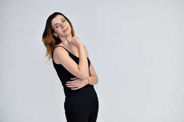 Portrait of a pretty brown-haired young woman on a white background in a black t-shirt. He stands in different poses, talking, different emotions.