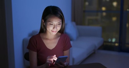 Woman use of mobile phone at home in the evening