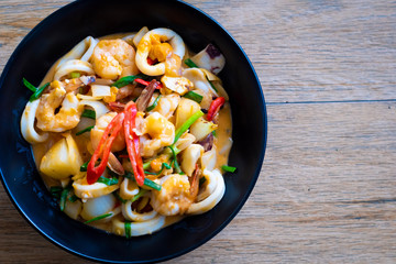 Stir Fried Squid with Salted Eggs on black plate on wooden table , Thai food.