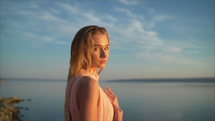 Young free girl in the morning on a background of water.. A beautiful girl raised her hand to pray. And promised myself. And the sun goes down. God bless you for the good.