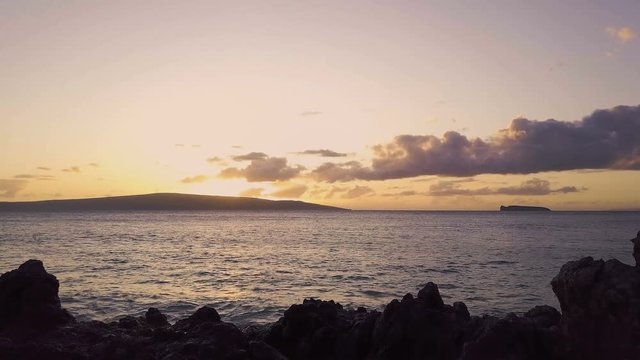 An Oceanside View Of A Sunset In The Tropics With Volcanic Rocks And Islands