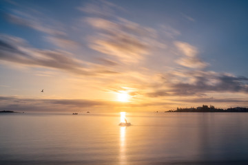 A Jet ski stops to admire the Sunset at Anse Vata Bay in New Caledonia in French Polynesia, South Pacific. Long exposure image..