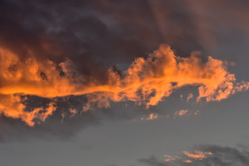 Dark cloud reflecting orange glow at sunset.
