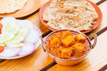 Indian Delicious Spicy Vegetarian Cuisine Paneer Toofani Also Know as Paneer Tufani, Toofani Paneer Masala or Dhaba Style Paneer Masala Served with Tandoori Roti on Wooden Yellow Background