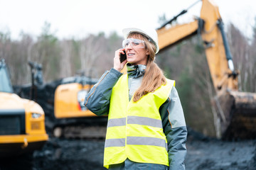 Worker woman in open-cast mining using phone