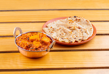 Indian Delicious Spicy Vegetarian Cuisine Paneer Toofani Also Know as Paneer Tufani, Toofani Paneer Masala or Dhaba Style Paneer Masala Served with Tandoori Roti on Wooden Yellow Background