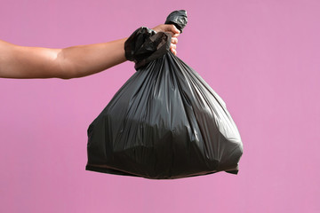 hand holding garbage bag isolate on pink background