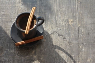 Grey cup of black coffee and cinnamon sticks on grey wooden boards or table. Morning, breakfast,...