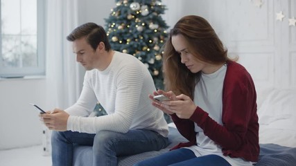 Busy family looking smartphones in private house. Married couple using phones