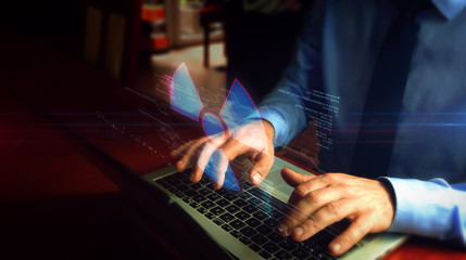 Man typing on keyboard with nuclear energy symbol hologram