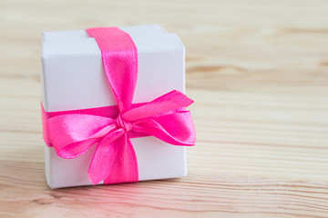 Gift box with a pink bow. Copy space. Festive background in a rustic style with a white gift box. The concept of holiday gifts.