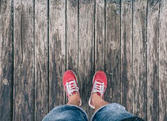 Feet in sneakers on a wooden floor. View from above.