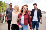 Group Of Student Friends Walking Across Bridge In City Together
