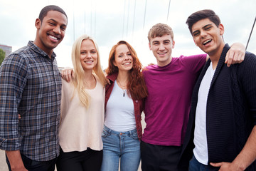 Portrait Of Student Friends Walking Across Bridge In City Together
