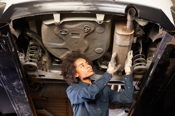 Afrikanische Mechatronikerin kontrolliert Auto Auspuff