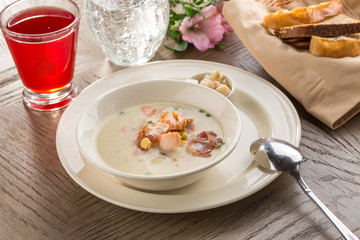 Chowder with Sweet Corn, Bacon and croutons and red drink on wooden table