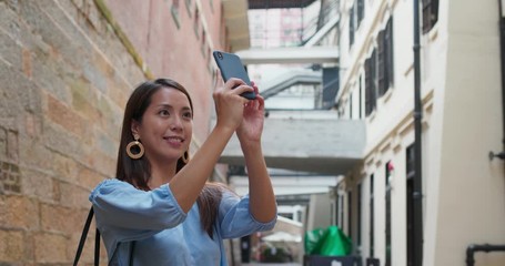 Woman tourist visit Hong Kong city and take photo on cellphone