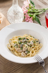 Pasta with chicken and cream mushroom sauce and red drink on wooden table