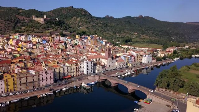 Drone aerial shot of the colourful town of Bosa in Sardinia.Bank turn right over the river temo with awesome green landscape. The Malaspina castle is dominating above the village.