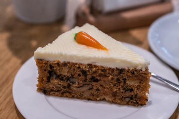 A carrot cake on a white plate in a cafe