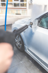 Close up of manual car wash with pressurized water in car wash.