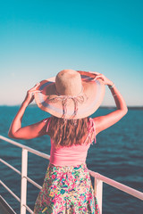 Cruise ship vacation woman enjoying travel vacation at sea. Free carefree happy girl looking at ocean and holding sunhat.