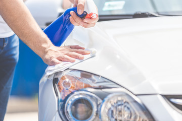 Man hands cleaning and spaying modern white car.