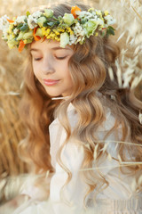 Naklejka premium Little girl with flowers. Teenager girl with a wreath of flowers on her head.