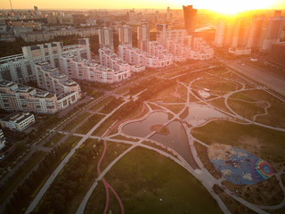 Newly built city park with playgrounds and ponds in the evening sun rays. Aerial view
